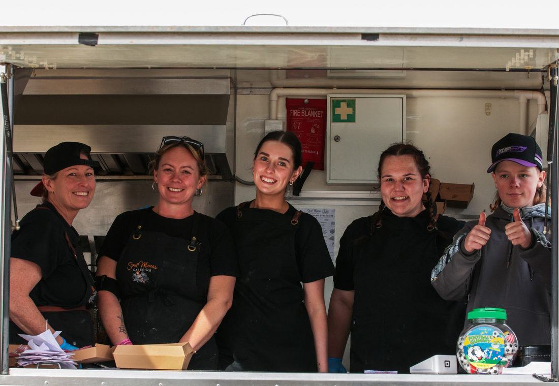 The Soul Mamas crew in the food trailer, aprons on, smiling